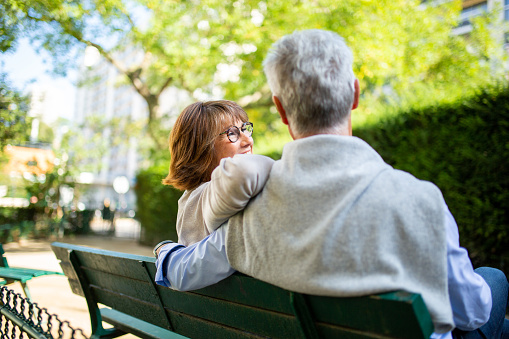 Portrait from back of couple sitting on park bench
