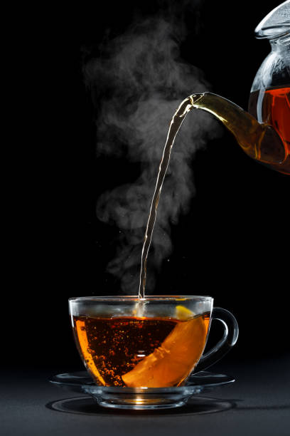 istock hot black tea pouring from teapot into glass cup with lemon 1675935003