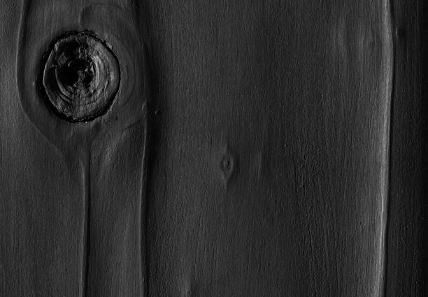 Big crack or hole in a dark black wooden plank