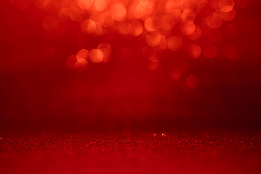 Defocused sequin light. Studio shooting of a creative bright red color background. It is textured color gradient. There are no text and no people, and have copy space for design. Its Suitable for commercial use. Christmas, New Year, Diwali festive celebrations themed backgrounds, wallpapers, templates for greeting cards, banners and posters and wrapping paper is apt.