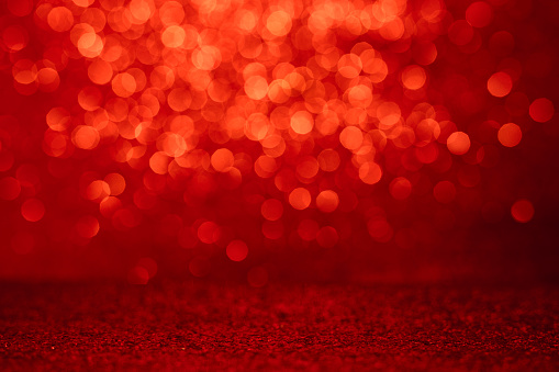 Defocused sequin light. Studio shooting of a creative bright red color background. It is textured color gradient. There are no text and no people, and have copy space for design. Its Suitable for commercial use. Christmas, New Year, Diwali festive celebrations themed backgrounds, wallpapers, templates for greeting cards, banners and posters and wrapping paper is apt.