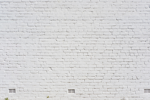 An old white brick wall with air ducts.