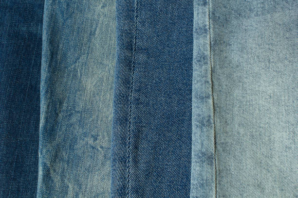 istock Blue jeans different shadows pants clothes pile background. Stack of blue jeans on shop desk 1675972081