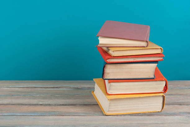 istock Book stacking. Open hardback books on wooden table and blue background. Back to school. Copy space for ad text 1675972631