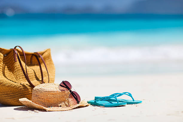 Beach vacation Straw hat, bag, sun glasses and flip flops on a tropical beach beach bag stock pictures, royalty-free photos & images