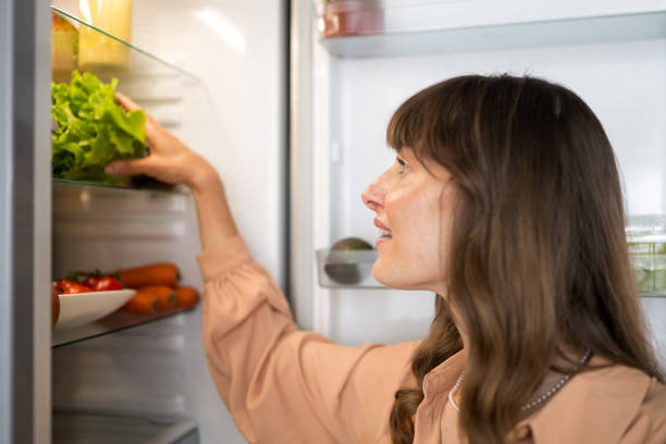 istock Woman takes out vegetable from refrigerator 1676004175