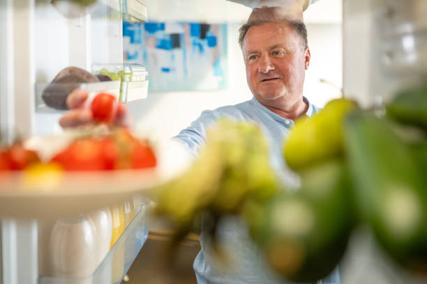 istock Man takes out tomato from refrigerator 1676004223
