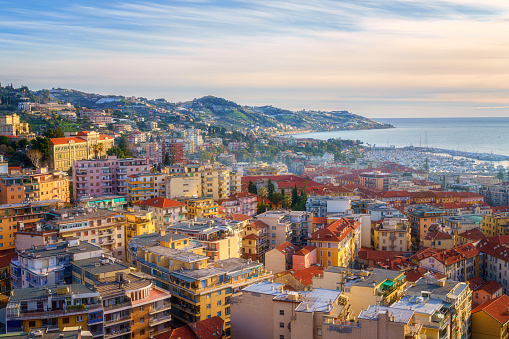 Panoramic view of Sanremo or San Remo from Pigna hill, Italian Riviera, Liguria, Italy. Scenic sunset landscape with city architecture, sea, green hills, blue water and sky, outdoor travel background