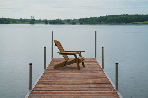 istock Adirondack chair at the end of a wooden dock. 1676063473
