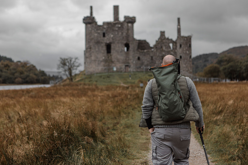 Handsome Male hiker outdoors at a ruined castle in Scotland