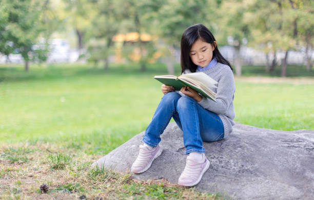 istock Reading Little Girl with Sitting on Stone 1676077093