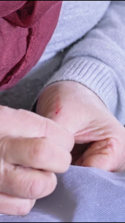 Close-up of a elderly woman sews by hand with a needle and thread. Selective focus.