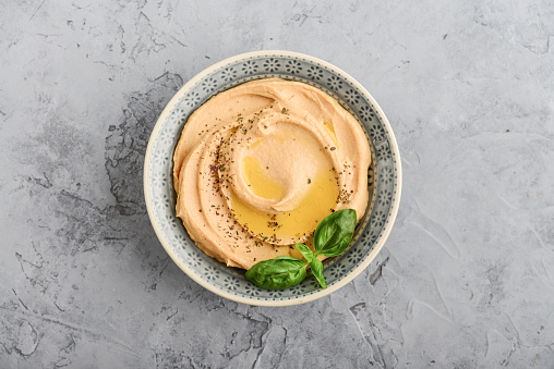 Bowls with hummus on gray background, top view