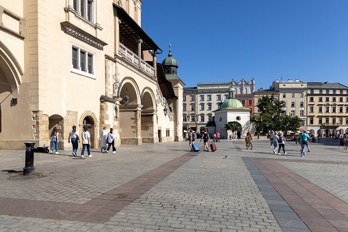 Krakow, Poland - September 6, 2023: Renaissance medieval Cloth Hall (Sukiennice) located at Main Square in the Old Town. Church of St. Adalbert in a distance