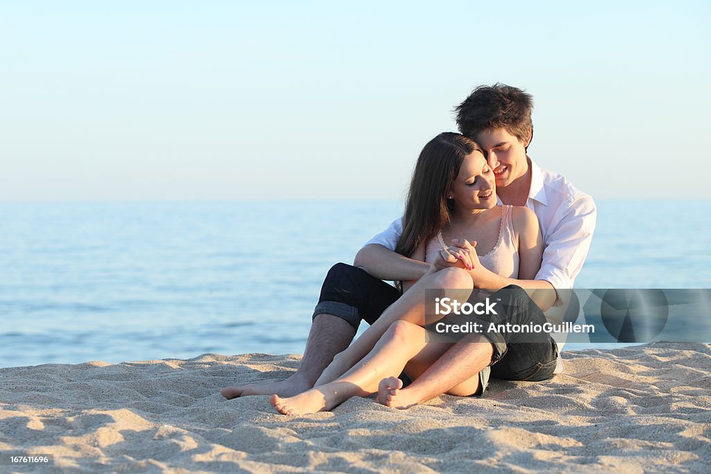 Couple embracing sitting on the sand Couple embracing sitting on the sand of the beach with the sea in the background Boyfriend Stock Photo