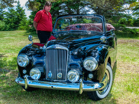 Chester, Nova Scotia, Canada - June 23, 2007 : A man stands near a 1953 Sunbeam Talbot 90 convertible and looks at it, Annual Graves Island Car Show at Graves Island Provincial Park, Chester, Nova Scotia Canada.
