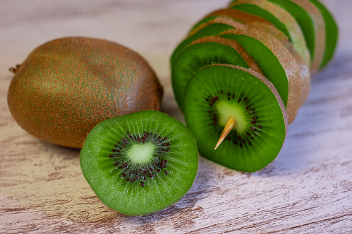 Closeup on ripe green kiwi fruits cut in slices on a wooden background. Healthy eating concept.