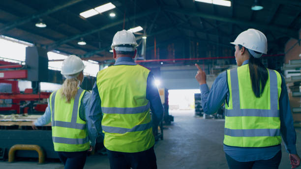istock Logistics group, back and pointing in warehouse, factory and planning with teamwork, ideas or talking. Man, women and storage for supply chain, production or helmet for safety in industrial workplace 1676137803