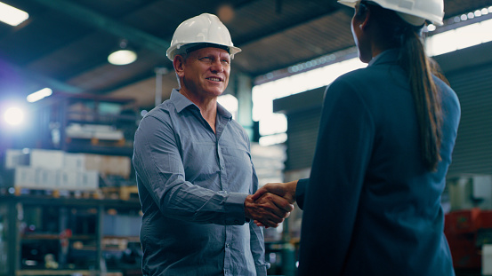 Engineering, handshake and teamwork with people in factory for manufacturing, meeting and partnership. Thank you, production and industrial with employees shaking hands in warehouse for agreement