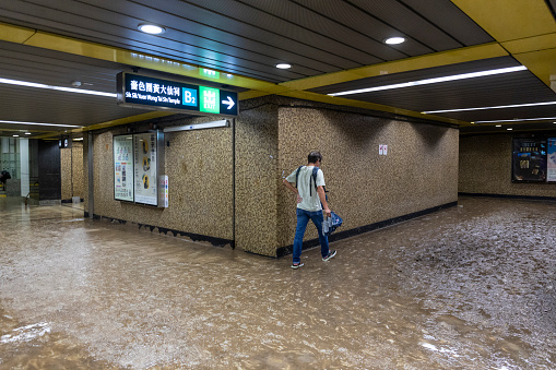 2023 Sept 8,Hong Kong. Man walks through mud in the Wong Tai Sin MTR station, following major flooding. Hong Kong  widespread flooding disrupting road and rail traffic.