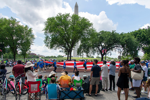 US Capitol Building, Washington DC, USA. Blue Sky, Puffy Clouds, Green Trees and Sightseeing Tourists are in the image.\n.