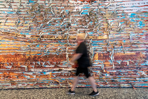 Washington DC, USA-July 5, 2023; Woman in blurred motion walking in front of colorful artwork Pickett’s Charge of Mark Bradford at the Hirshhorn Museum and Sculpture Garden