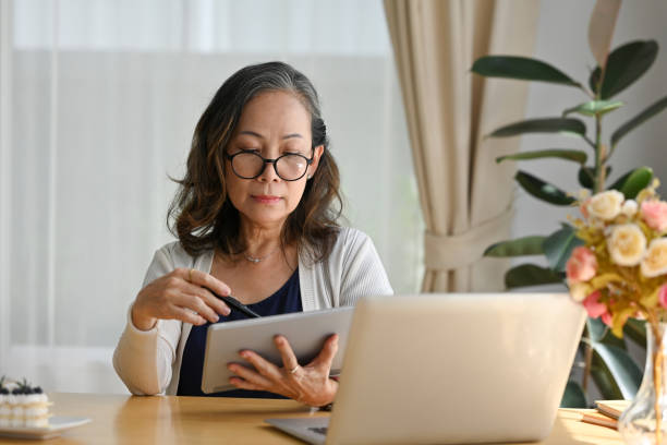 istock Old woman at home using laptop wearing eyeglasses working on computer. 1676160699