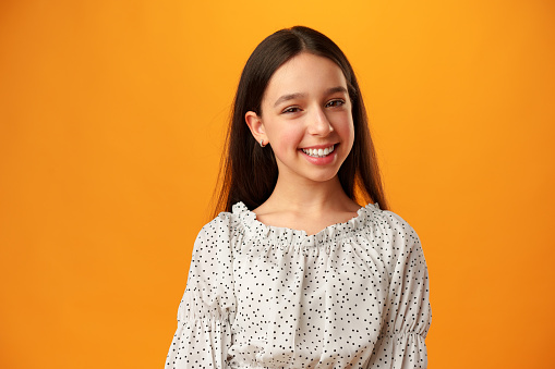 Photo of teen girl smiling portrait against yellow background in studio close up