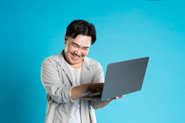 istock Image of Asian man using laptop on blue background 1676172352