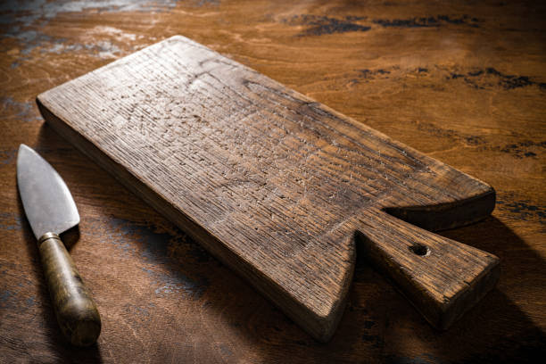 Wooden cutting board or chopping board and kitchen knife on rustic wood table low key kitchenware