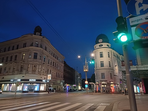 Vienna, Austria - June 7, 2023: Street life in center of Vienna city, Austria with buildings and shops. Cityscape at night. The traffic light is green.