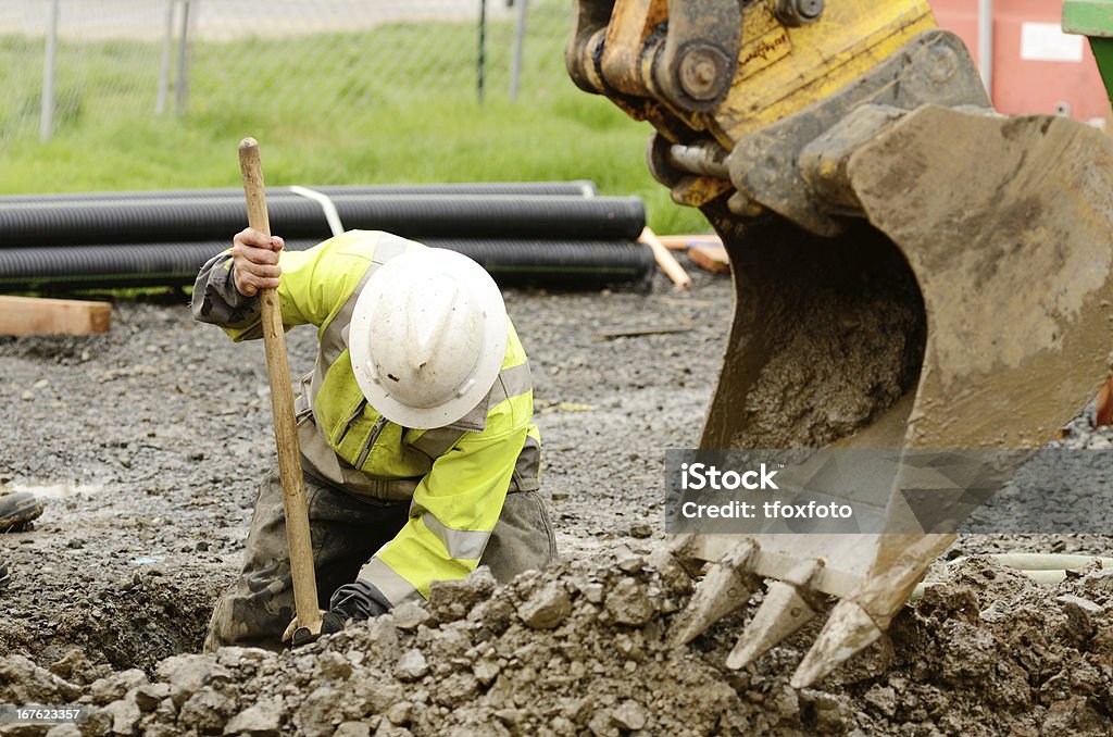 Construction worker digging dirt out with the help of crane Worker using a small tracked excavator to dig a hole to fix a water leak at a large commercial housing development in Oregon Digging Stock Photo