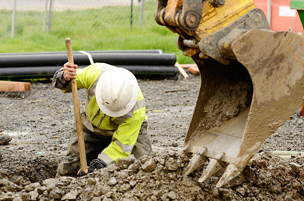 Construction worker digging dirt out with the help of crane Worker using a small tracked excavator to dig a hole to fix a water leak at a large commercial housing development in Oregon backhoe photos stock pictures, royalty-free photos & images