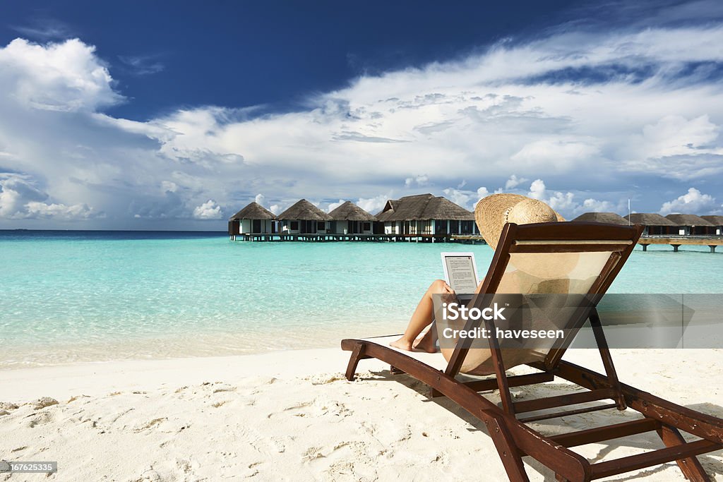 Young woman with tablet pc at the beach Young woman in hat with tablet pc at the beach Digital Tablet Stock Photo