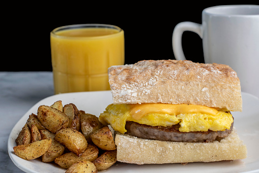 scramb;e egg  and sausage patty on ciabatta  served with home fries