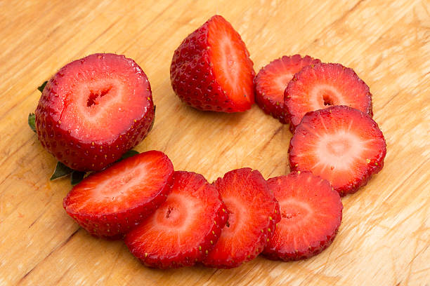 Slices of ripe and juicy strawberry on bamboo cutting board stock photo