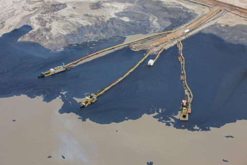 Crude oil seen separated from sand for collection. Tailings ponds are used to separate the heavy oil bitumen from the sticky sand mined from around the area.  Near Fort McMurray, Alberta.