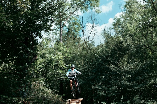 Brave man jumping with a mountain bike in the wild nature