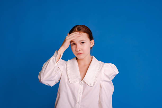 istock thinking student girl touching forehead with hand on light blue studio background 1676360119