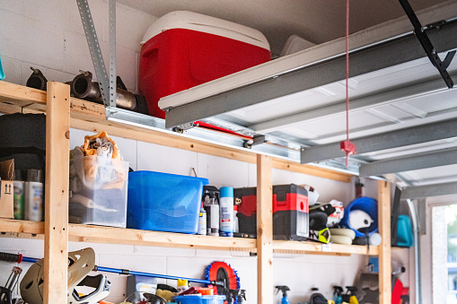This is a photograph of shelves with household items stored in an open one car garage door on a bright sunny day.