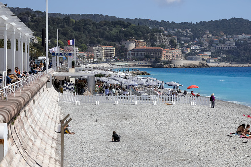 Nice, France - April 26, 2023: Seaside view with beach in the city. The peninsula and its buildings are visible in the distance