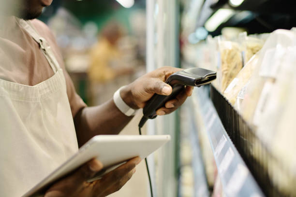 Supermarket worker scanning codes of goods Close-up of African American supermarket worker using tablet pc to scan codes of goods on shelves merchandiser stock pictures, royalty-free photos & images