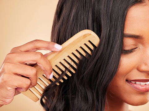 Comb, closeup and young woman in studio with clean salon treatment hairstyle for wellness. Health, hair care and zoom of female model with cosmetic tool for haircut maintenance by brown background.