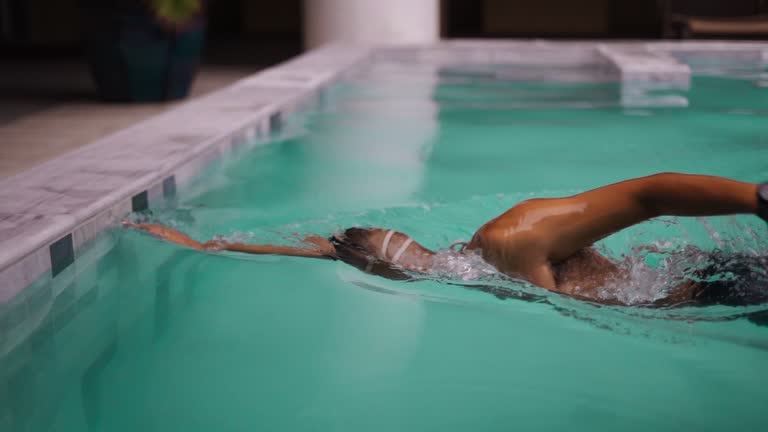 Young strong sport man swimming in hotel swimming pool for muscle recovery.