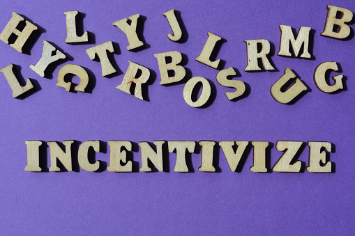 Incentivize, word in wooden alphabet letters isolated on purple background as banner headline