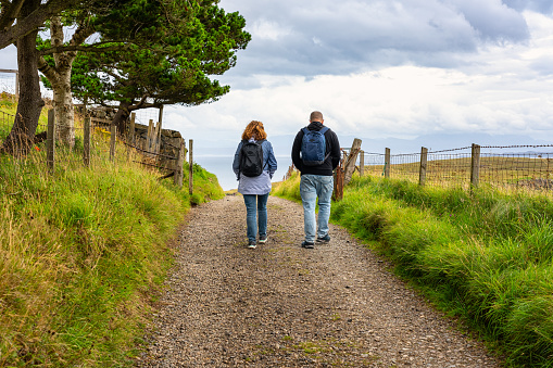 A couple of men and women walking along a path on the Isle of Skye, Scotland, UK