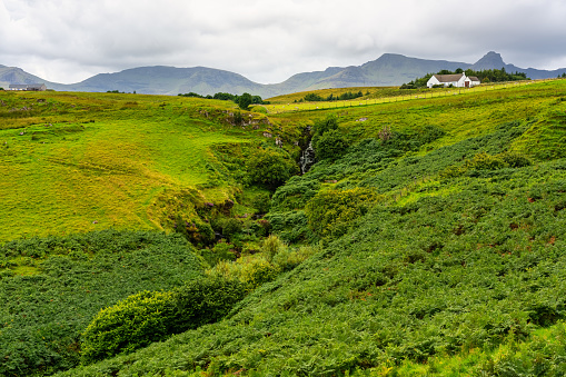 Green landscape with high mountains and cottages on the Isle of Skye, Scotland, UK
