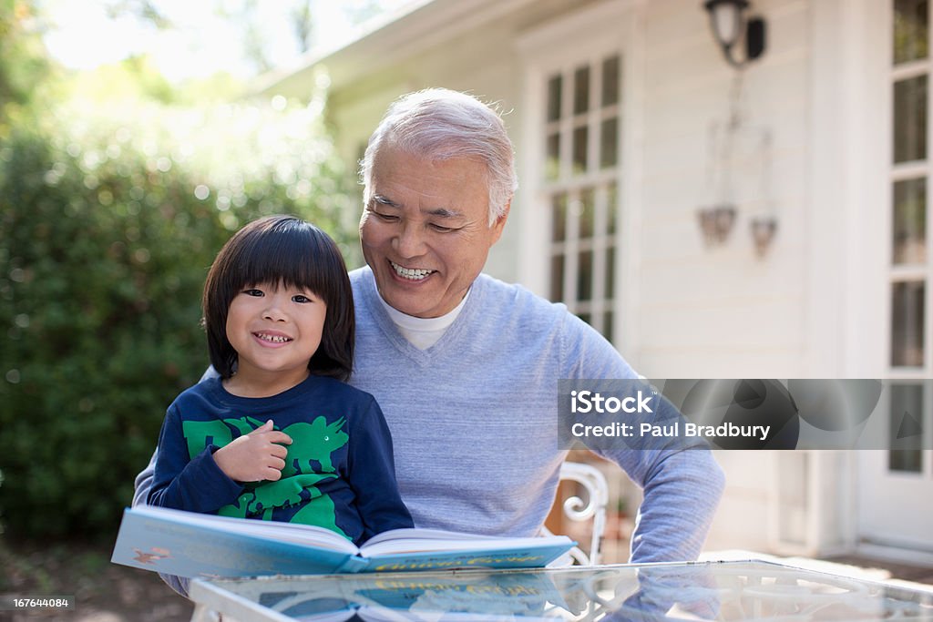 Older man and grandson reading together  Asian and Indian Ethnicities Stock Photo