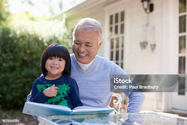 Older Man And Grandson Reading Together Stock Photo - Download Image Now - Asian and Indian Ethnicities, Senior Adult, Grandfather