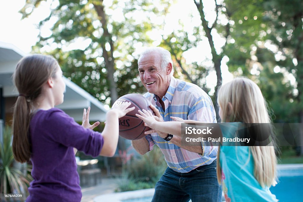 Anziani uomo giocando a basket con granddaughters - Foto stock royalty-free di Tendere la mano